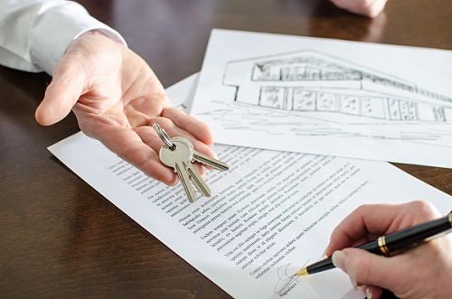 Realtor showing house keys and woman signing a real estate contract